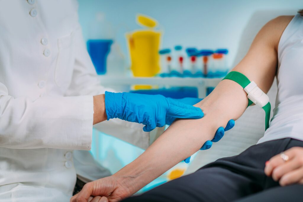 Preparation for phlebotomy procedure, female patient and medical nurse wearing protective masks